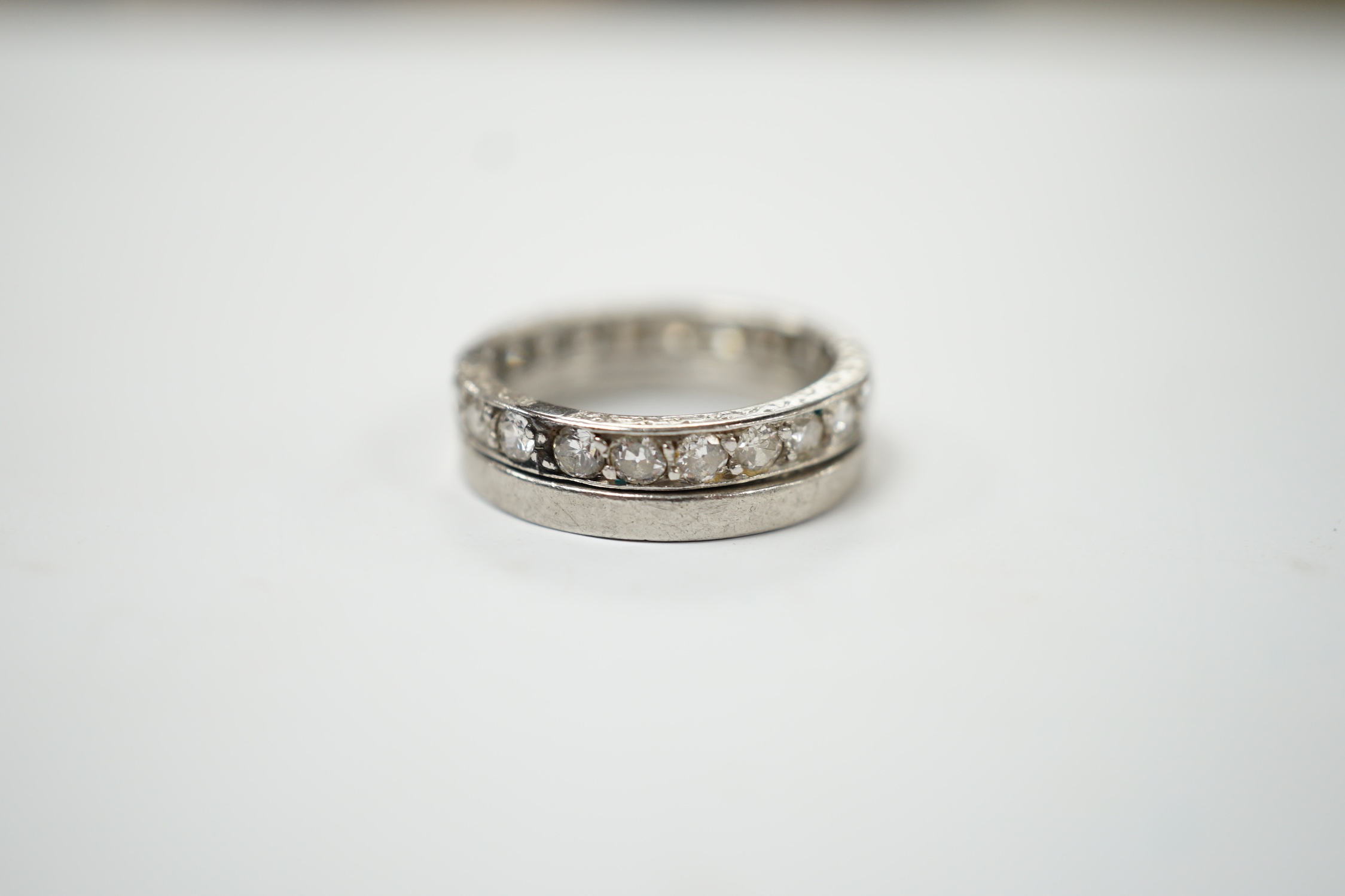 A white metal and diamond set full eternity ring, size K and an unmarked white metal band. Fair condition.
